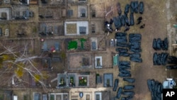 Oficerët e policisë ukrainase përpiqen të identifikojnë civilët e vrarë gjatë pushtimit të qytetit Bucha nga forcat ruse (6 prill 2022)