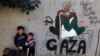 Anak-anak pengungsi Palestina berdiri di samping lukisan mural karya seniman Amal Abo di Rafah di selatan Jalur Gaza, pada 31 Desember 2023. (Hewan-hewan di kebun binatang di Rafah, kota di Gaza Selatan, sekarat karena kelaparan. (Foto: Ilustrasi/AFP)
