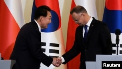 South Korea's President Yoon Suk Yeol shakes hands with Polish President Andrzej Duda, as they attend a joint press conference at the Presidential Palace in Warsaw, Poland, July 13, 2023.