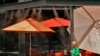 A woman walks under misters outside a restaurant, July 12, 2023 in Gilbert, Ariz. Even desert residents accustomed to scorching summers are feeling the grip of an extreme heat wave smacking the U.S. Southwest this week.