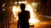 A person stands near a burning container as people protest following the death of Nahel, a 17-year-old teenager killed by a French police officer in Nanterre during a traffic stop, and against police violence, in Paris, France, June 30, 2023. 
