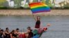 A woman holds a Rainbow flag after competing in a dragon boat during the annual Dragon Boat Festival in Taipei, Taiwan, June 22, 2023. 