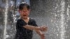 A girl reacts as she plays in a fountain at a shopping mall in Beijing, June 23, 2023. 