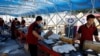 FILE - Delivery workers sort packages on a conveyor belt, ahead of the '618' shopping festival, at a logistics station in Beijing, June 12, 2023. 