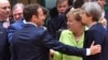 French President Emmanuel Macron (left) puts his hand on the shoulder of British Prime Minister Theresa May during a round table meeting at an EU summit in Brussels, June 22, 2017. German Chancellor Angela Merkel stands between them.