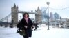 Orang-orang berjalan di jalur tertutup salju di dekat Tower Bridge, saat cuaca dingin berlanjut di London, Inggris, 12 Desember 2022. (REUTERS/Henry Nicholls)