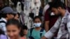 Seorang gadis mengenakan masker di antara kerumunan warga yang berlalu-lalang di distrik perbelanjaan Mumbai, India, Kamis, 22 Desember 2022. (AP /Rafiq Maqbool)