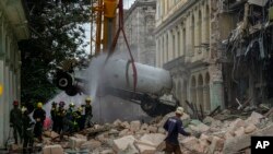 Bombeiros atiram água a um camião-cisterna para arrefecê-lo, à medida que tentam removê-lo em segurança do lugar onde aconteceu a explosão fatal que destrui o hotel de 5 estrelas Saratoga, em Havana, 6 Maio, 2022.