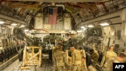 На цьому роздатковому фото, наданому Корпусом морської піхоти США, показано, як морські піхотинці США завантажують буксировану 155-мм гаубицю M777 у вантажний відсік C-17 Globemaster III ВПС США на базі March Air Reserve, Каліфорнія, 21 квітня, 2022.