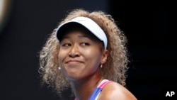 Naomi Osaka dari Jepang tersenyum saat pertandingan putaran pertama melawan Camila Osorio dari Kolombia di kejuaraan tenis Australia Terbuka di Melbourne, Australia, Senin, 17 Januari 2022. (Foto: AP)