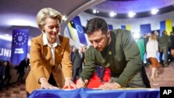 Presiden Ukraina Volodymyr Zelenskyy (kanan) dan Presiden Komisi Eropa Ursula von der Leyen menulis keinginan mereka pada bendera Ukraina saat berlangsungnya KTT UE-Ukraina di Kyiv, Ukraina, Kamis, 2 Februari 2023. ((Kantor Pers Kepresidenan Ukraina via AP)