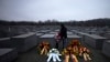Seorang ayah dengan kedua anaknya berdiri di karangan bunga pada hari Peringatan Holokos Internasional di Berlin, Jerman, 27 Januari 2023.