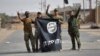 FILE - Shi'ite Popular Mobilization Forces (PMF) fighters remove an Islamic State flag after liberating the city of Al-Qaim, Iraq, Nov. 3, 2017. 