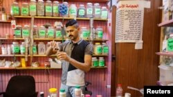 Hassan Abed Ali mixes different liquids meant for treatments, at his shop in Baghdad, Iraq, June, 11, 2023