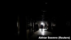 Seorang pria berjalan di sebuah gedung saat listrik padam di Karachi, Pakistan, 12 April 2018. (Foto: REUTERS/Akhtar Soomro)