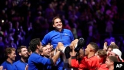 Roger Federer dari tim Eropa diangkat oleh sesama pemain setelah bermain dengan Rafael Nadal dalam pertandingan ganda Piala Laver melawan Jack Sock dan Frances Tiafoe dari Tim Dunia di arena O2 di London, 23 September 2022. (Foto: AP)