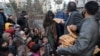 Seorang perempuan Afghanistan menerima bantuan sepotong roti di depan toko roti di antara kerumunan di Kabul, Afghanistan, 31 Januari 2022. (Foto: REUTERS/Ali Khara)