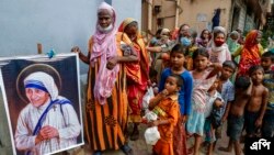 ফাইল ছবি- গৃহহীন মানুষ মিশনারিজ অফ চ্যারিটির প্রতিষ্ঠাতা সেন্ট তেরেসার একটি প্রতিকৃতির পাশে জড়ো হয়ে দাঁড়িয়ে আছে.২৬ আগস্ট ২০২১। (ফাইল ছবি-এপি/বিকাস দাস)