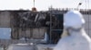 A member of the media tour group wearing a protective suit and a mask looks at the No. 3 reactor building at Tokyo Electric Power Co's (TEPCO) tsunami-crippled Fukushima Daiichi nuclear power plant in Okuma, Fukushima Prefecture, Japan, Feb. 10, 2016. 