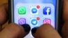 Une femme tient un téléphone androïde, l'écran affiche les icônes des applications de réseaux sociaux Facebook, Instagram et autres, le 23 mars 2018 à Moscou. 