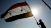 A Syrian protester stands on top of a building as he waves a Syrian flag, during a demonstration against a U.S. raid at a village near the Syrian-Iraqi border, in Damascus, Syria, Oct. 30, 2008. Hundreds of Syrian riot police ringed the shuttered and clos