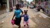 FILE - A child sips on a refreshment as she is walked home from school, in Cap-Haitien, Haiti, April 17, 2024. 