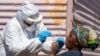 FILE - A woman opens her mouth for the heath worker to collect a sample for coronavirus testing during the screening and testing campaign aimed to combat the spread of COVID-19 at Lenasia South, south Johannesburg, South Africa, April 21, 2020.