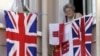 FILE - A woman resident of Gibraltar looks out of a window behind flags of England and Gibraltar, Aug. 4, 2004.