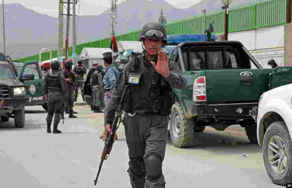 An Afghan policeman prevents journalists from approaching Cure International Hospital in Kabul, Afghanistan, April 24, 2014.