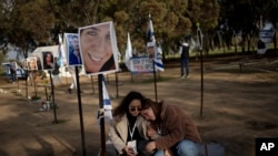 Dua perempuan Israel saling berusaha menenangkan satu sama lain saat berkunjung ke monumen penanda bagi warga Israel yang tewas terbunuh dalam serangan pada 7 Oktober 2023, di Re'im, selatan Israel, pada 24 Januari 2024. (Foto: AP/Maya Alleruzzo)