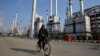 FILE - Iranian oil worker rides his bicycle at the Tehran's oil refinery south of the capital Tehran, Iran.