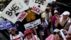Anti-government protesters carry signs against ousted Prime Minister Yingluck Shinawatra as they march in central Bangkok, May 8, 2014.