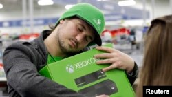 FILE - A man hugs his new Xbox One after he purchased it at a Best Buy, Nov. 22, 2013, in Evanston, Illinois. 