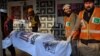Pakistani rescue workers remove a body from the site of a grenade attack at a movie theater in Peshawar, Feb. 11, 2014.