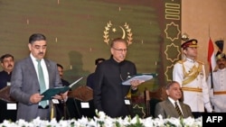 ২০২৩ সালের ১৪ আগস্টে পাকিস্তানের প্রেস ফ্রিডম ইনফরমেশন দফতরের তোলা ও প্রকাশিত এই ছবিতে পাকিস্তানের রাষ্ট্রপতি আরিফ আলভি (মাঝে) আনওয়ারুল হক কাকারকে তত্ত্বাবধায়ক প্রধানমন্ত্রী হিসেবে শপথ পাঠ করাচ্ছেন।