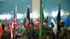 An Afghanistan National Army soldier (C) and ISAF soldiers hold flags during a change of command ceremony at the ISAF headquarters in Kabul on February 10, 2013. 