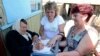 Members of the Ukrainian election commission assist an elderly voter before she casts her vote in a mobile ballot box in the village of Nyzkovka, May 25, 2014. 