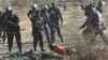 South African policemen give instructions to an injured miner after striking miners were shot outside a South African mine in Rustenburg, 100 km northwest of Johannesburg on August 16, 2012. 