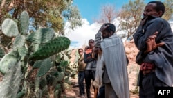 FILE - People mourn near a mass grave of victims of a massacre allegedly perpetrated by neighboring Eritrean soldiers, in the village of Dengolat, Ethiopia, February 26, 2021.