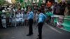 Policemen stand guard near supporters of the Pakistan Muslim League - Nawaz (PML-N) party during an election campaign rally in Islamabad, May 5, 2013.
