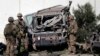 U.S. troops keep watch near a damaged vehicle at the site of suicide attack in Kabul, Afghanistan, Sept. 16, 2014.
