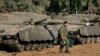 FILE - An Israeli soldier walks past tanks near the Israel and Gaza border, July 10, 2014. The United States and Israel are negotiating a new deal regarding military aid.