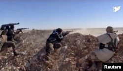 FILE - This photo from a video provided by the Syria Democratic Forces (SDF), shows fighters from the SDF opening fire on an Islamic State group's position, in Raqqa's eastern countryside, Syria, March 6, 2017.