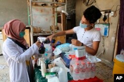 Duhaa Mayaa, left, and her son Youssef prepare a Pepsi wash to treat tear-gas exposure for injured protesters, in their home in Basra, Iraq, Sept. 9, 2018.