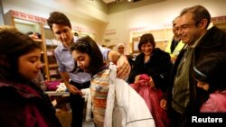 El primer ministro de Canadá, Justin Trudeau, ayuda a una joven refugiada siria a probarse un abrigo. La niña llegó con su familia procedente de Beirut, con el primer grupo de refugiados sirios que llegó a Canadá en un avión militar, en 2015.