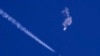 Sisa-sisa balon besar melayang di atas Samudra Atlantik, tepat di lepas pantai Carolina Selatan, dengan jet tempur dan contrailnya terlihat di bawahnya, 4 Februari 2023. (Chad Fish via AP)