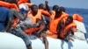 FILE - Migrants wearing life vests float in an inflatable boat during a rescue operation from the Aquarius vessel of SOS Mediterranee NGO and MSF (Doctors Without Borders) in the sea some 25 Nautical miles (29 miles, 46 kilometers) north of the Libyan coast, Aug. 27, 2017.