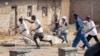 FILE - Members of the Imbonerakure pro-government youth militia chase after opposition protesters, unhindered by police, in the Kinama district of the capital Bujumbura, Burundi, May 25, 2015.