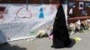 A woman walks past messages attached to a wall near the scene of an attack next to Finsbury Park Mosque, in north London, June 20, 2017. 