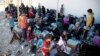 FILE - Displaced women and children sit on the ground at a collection point for internal refugees west of Mosul, Iraq, Aug. 12, 2017. 